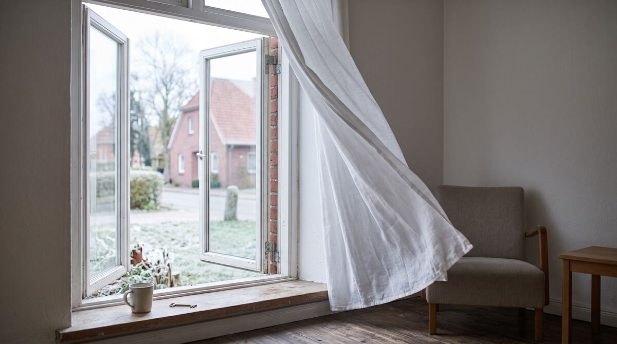Weit geöffnetes Fenster beim Stoßlüften, die Gardine weht nach innen